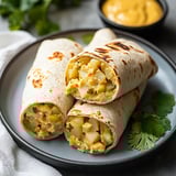 Two burritos with potatoes and cheese on a plate.