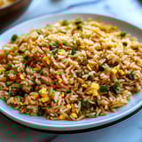 A white plate with rice and eggs on it.