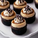 A plate of cupcakes with white frosting and chocolate toppings.