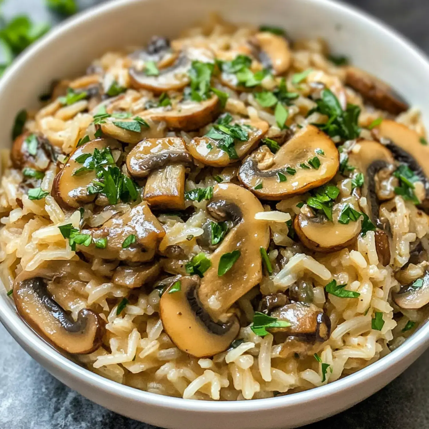 A bowl of cooked rice topped with sautéed mushrooms and garnished with chopped parsley.