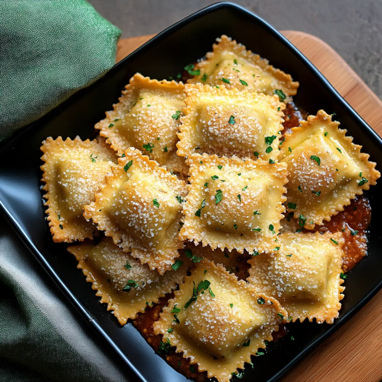 A black bowl filled with ravioli topped with shredded cheese and garnished with parsley.