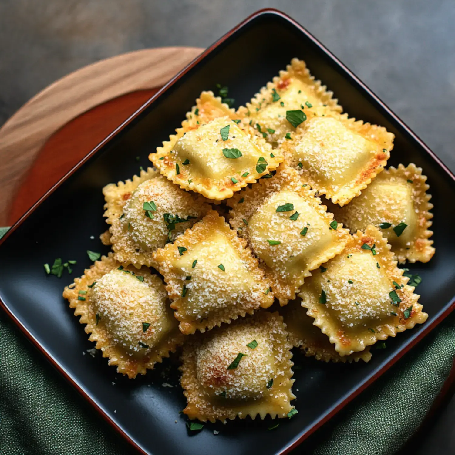 A black bowl filled with golden-brown, breaded ravioli topped with chopped parsley sits on a wooden surface.