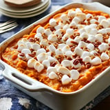 A casserole dish filled with sweet potato topping covered in mini marshmallows and chopped pecans.