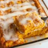 A piece of glazed pumpkin cake is being lifted from a pan.